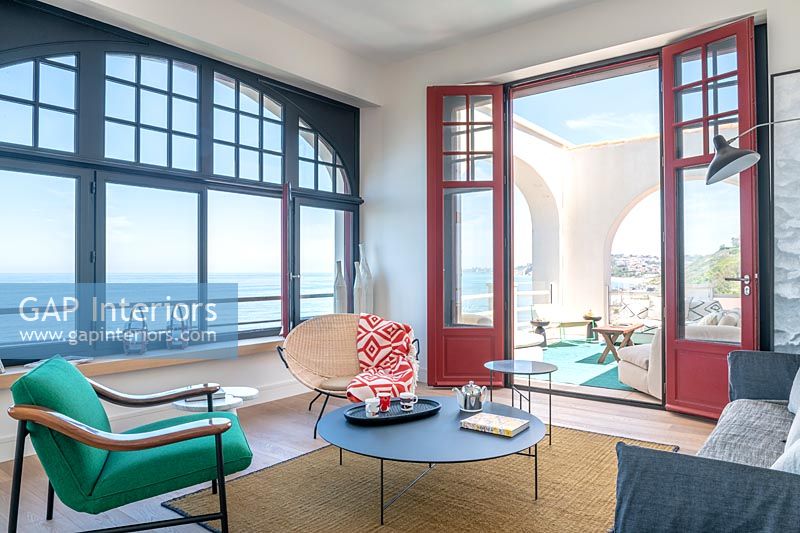 Salon moderne avec vue à travers des portes françaises ouvertes sur la terrasse et vue sur la mer