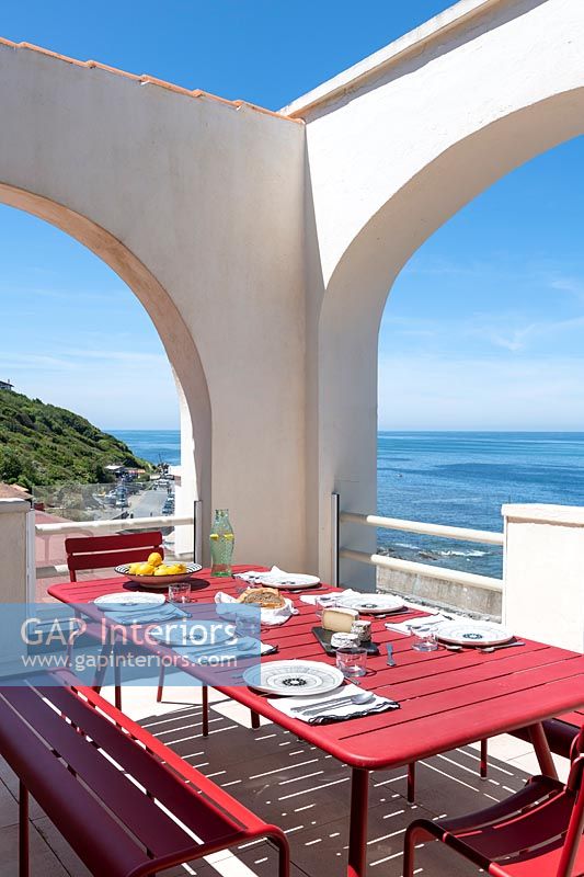 Table à manger extérieure dressée pour le déjeuner sur une terrasse fortifiée avec vue sur la mer
