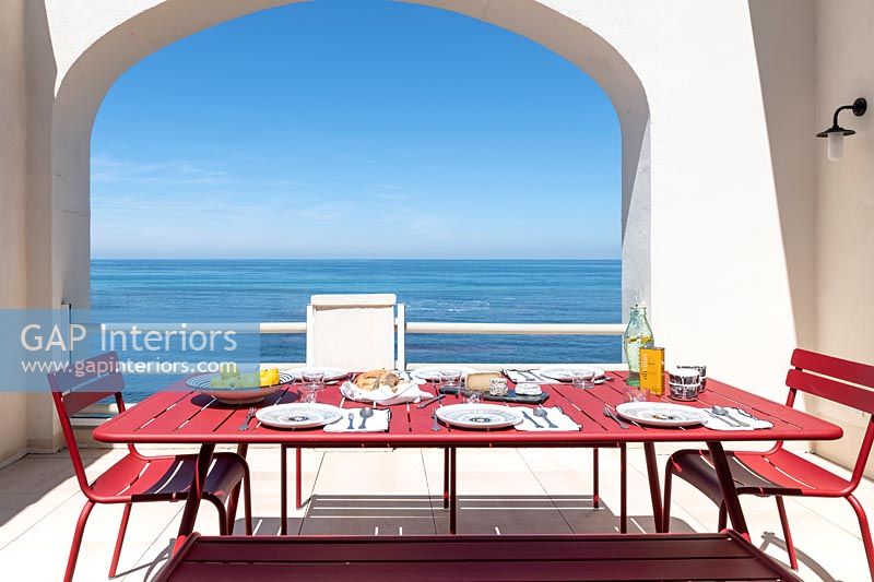 Salle à manger extérieure avec vue sur la mer - table dressée pour le déjeuner