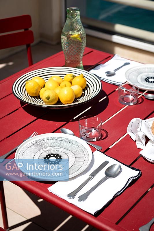 Citrons dans un bol noir et blanc sur une table à manger extérieure rouge