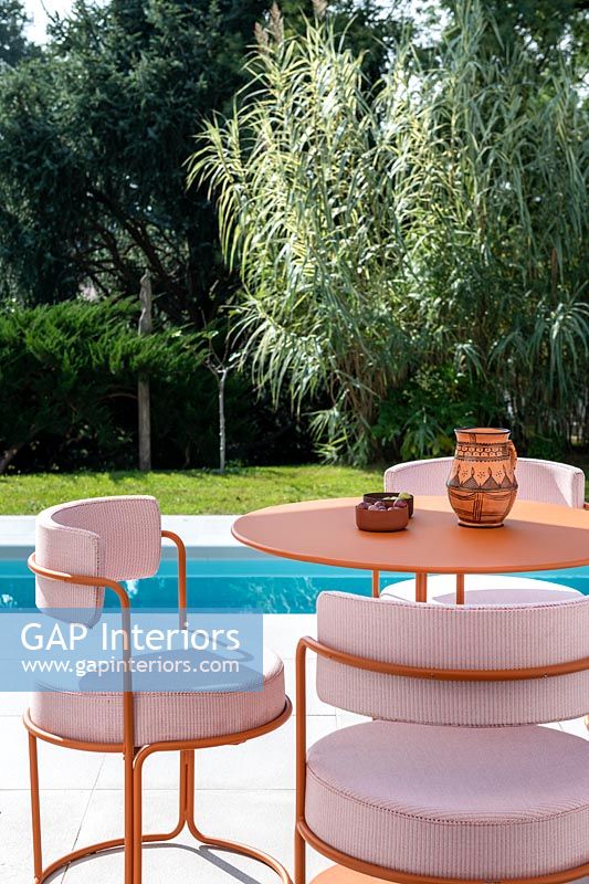 Chaises rembourrées et table de style café sur terrasse à côté de la piscine