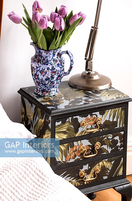 Table de chevet peinte de façon décorative avec une cruche vintage pleine de tulipes roses
