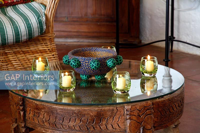 Bougies dans de petits verres sur table basse en bois sculpté