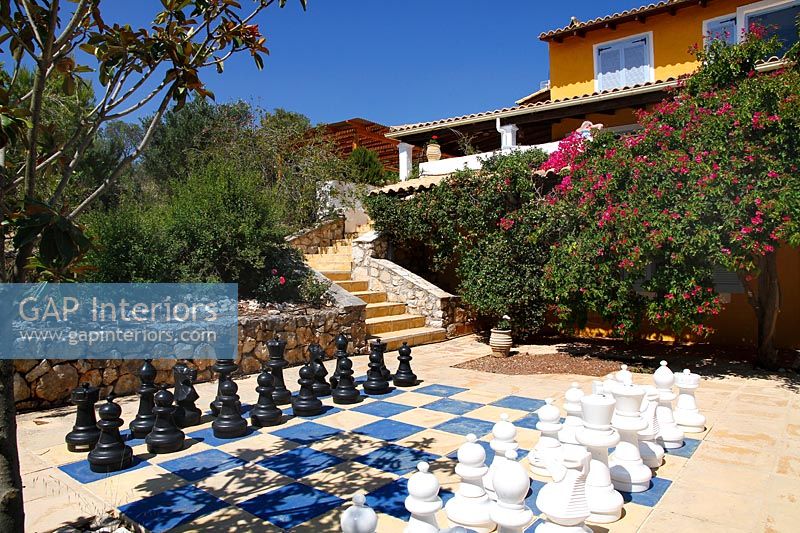 Grand jeu d'échecs en plein air sur terrasse à côté d'une maison de style méditerranéen