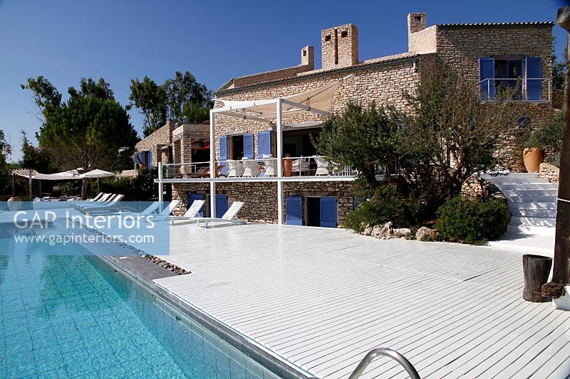 Maison de campagne en pierre avec piscine moderne, terrasse et fauteuils inclinables