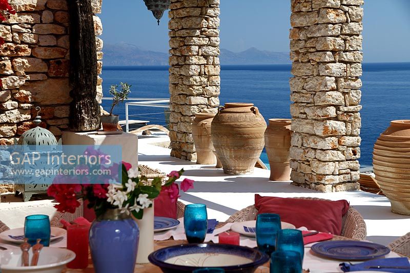Table à manger extérieure dressée pour le déjeuner sur une terrasse couverte avec vue sur la mer