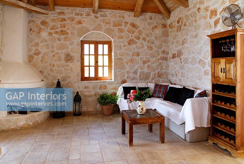 Murs en pierres apparentes et meubles en bois dans un salon de campagne avec cheminée rustique