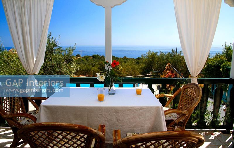 Terrasse couverte avec table et vue sur la piscine et la mer au-delà