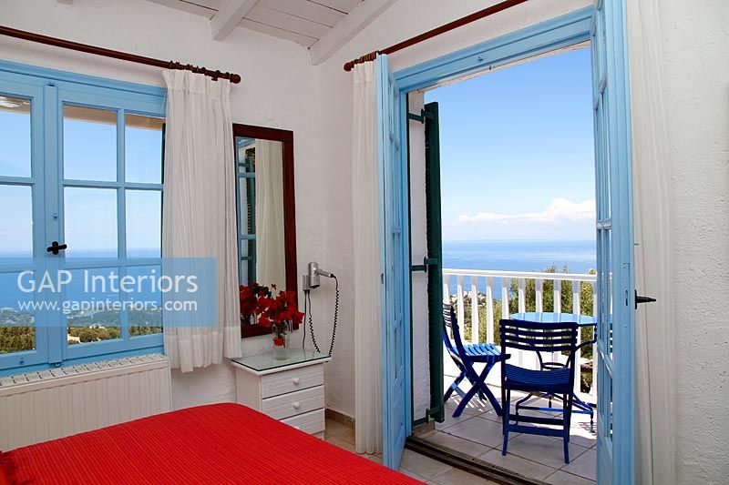 Chambre de campagne méditerranéenne avec portes-fenêtres ouvertes sur balcon avec vue sur la mer