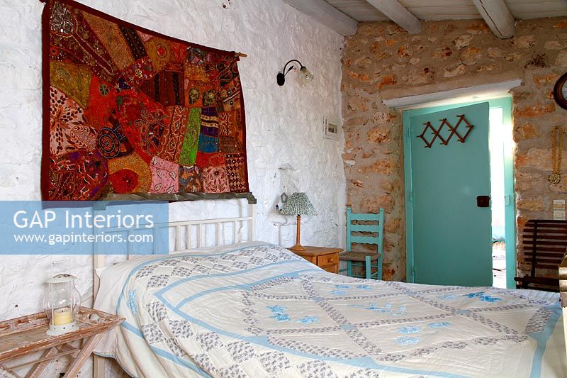 Chambre de campagne avec tenture murale en tissu coloré au-dessus du lit