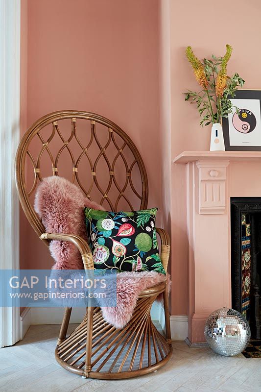Fauteuil en osier à dossier haut dans le salon peint en rose