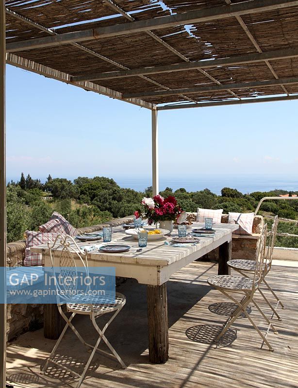 Table à manger extérieure sur terrasse en bois avec vue sur la côte