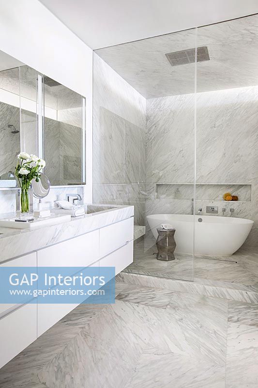 Salle de bains contemporaine en marbre blanc et gris avec baignoire à l'intérieur d'une enceinte en verre