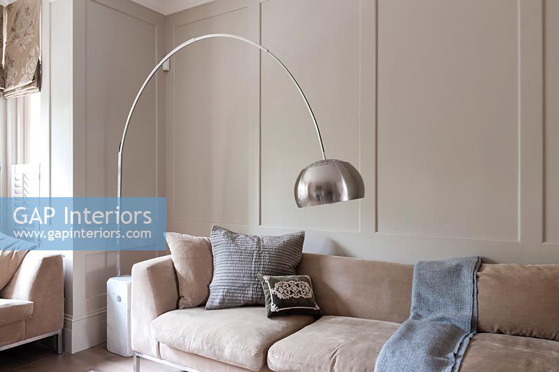 Salon moderne avec grand lampadaire argenté sur canapé