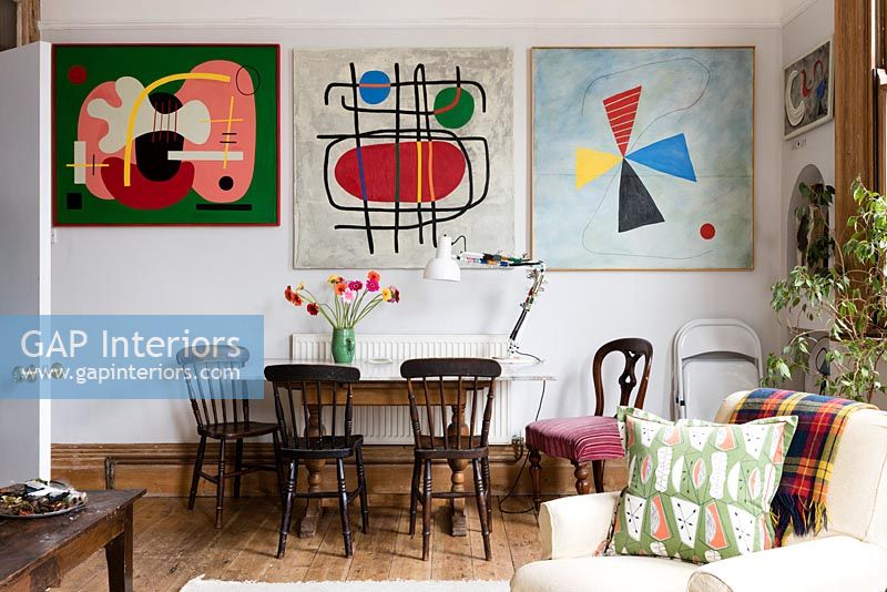 Salle à manger et mur d'œuvres d'art modernes colorées dans un espace de vie ouvert