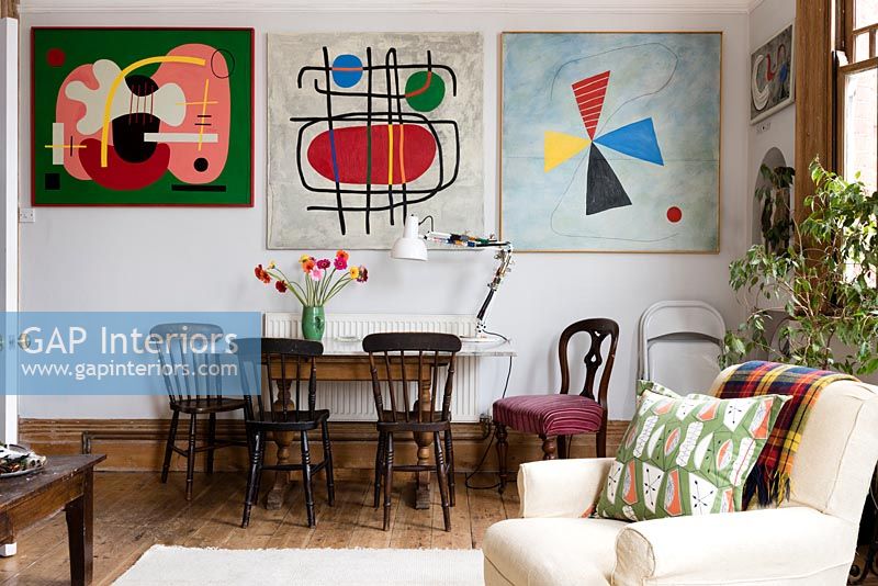 Salle à manger et mur d'œuvres d'art modernes colorées dans un espace de vie ouvert. Coussin de Nichollette Yardley-Moore www.vintagecushions.com