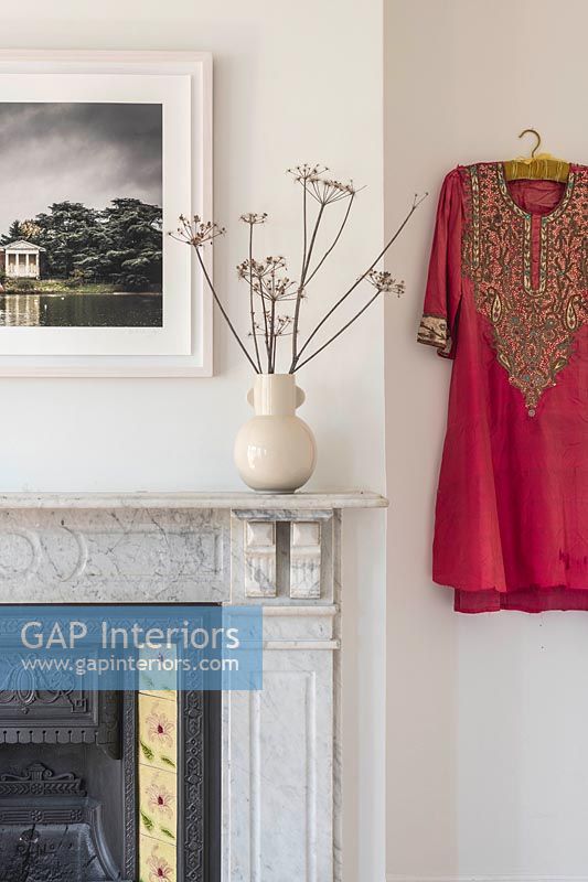 Robe de style indien rouge vif sur le mur du salon à côté de la cheminée