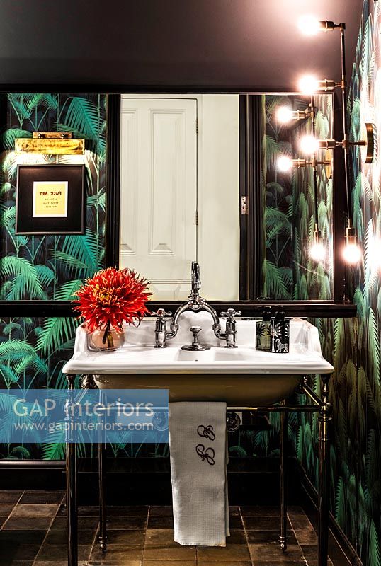 Salle de bain éclectique avec papier peint tropical et miroir éclairé au-dessus du lavabo