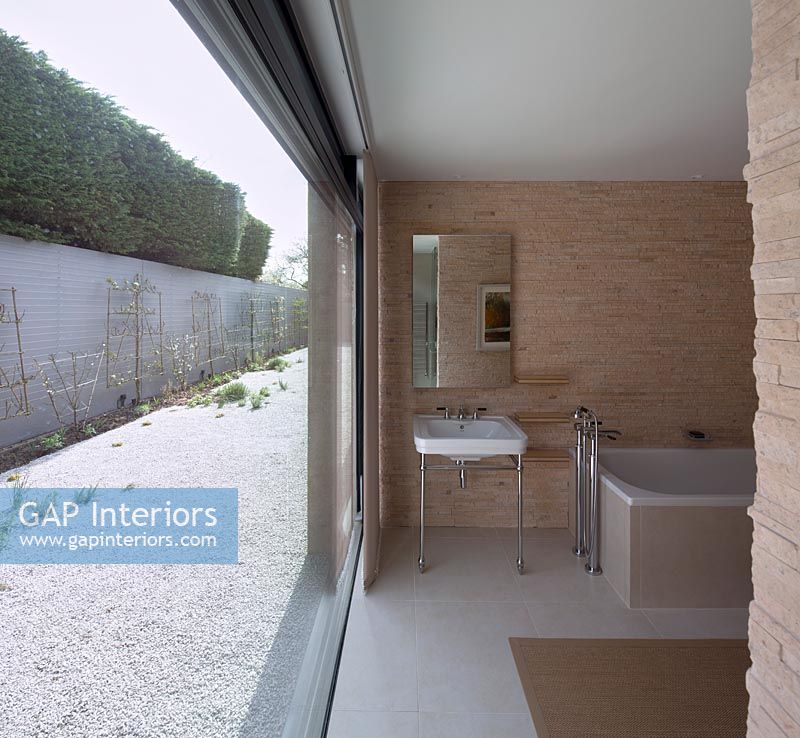 Salle de bain contemporaine avec grande porte-fenêtre ouverte donnant sur le jardin clos