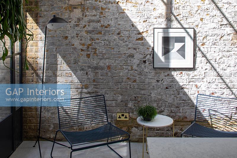 Chaises basses et table dans un salon moderne avec mur de briques apparentes