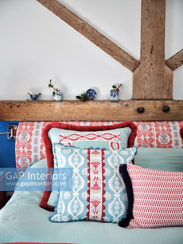 Coussins et tête de lit à motifs bleus et rouges dans la chambre de campagne