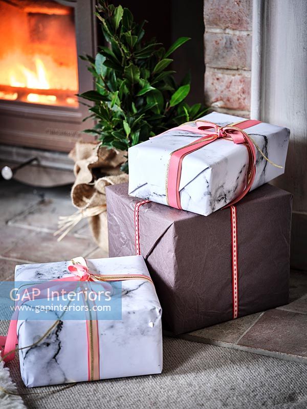 Détail de cadeaux de Noël emballés à côté d'un poêle à bois allumé