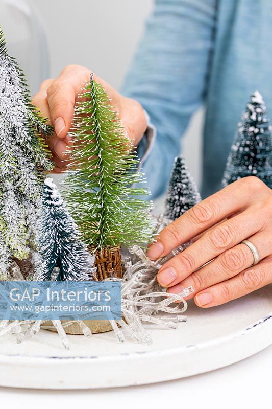 Femme ajoutant de faux arbres de Noël miniatures au bac