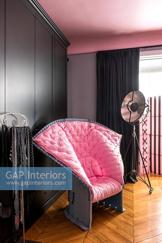 Chaise rembourrée rose moderne inhabituelle dans une chambre noire et rose