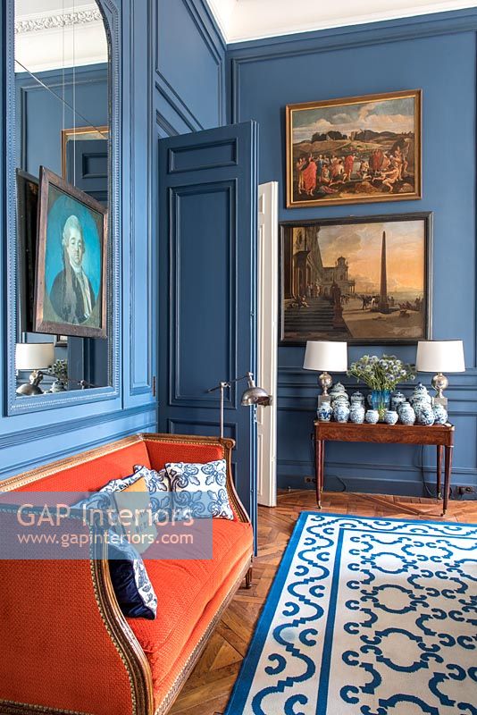 Canapé orange vif dans le salon classique peint en bleu