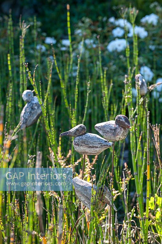Ornements d'oiseaux parmi les hautes herbes dans le jardin de campagne