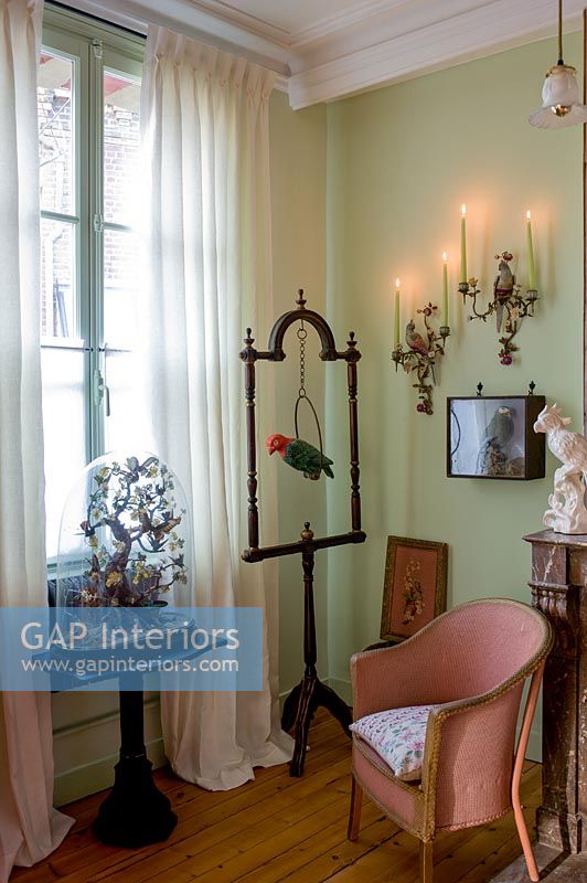 Mur peint en vert et chaise ancienne rose entourée d'ornements