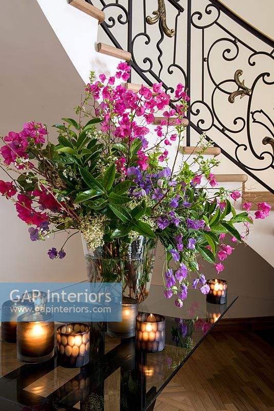 Détail de l'arrangement floral et des bougies chauffe-plat sur la table du couloir