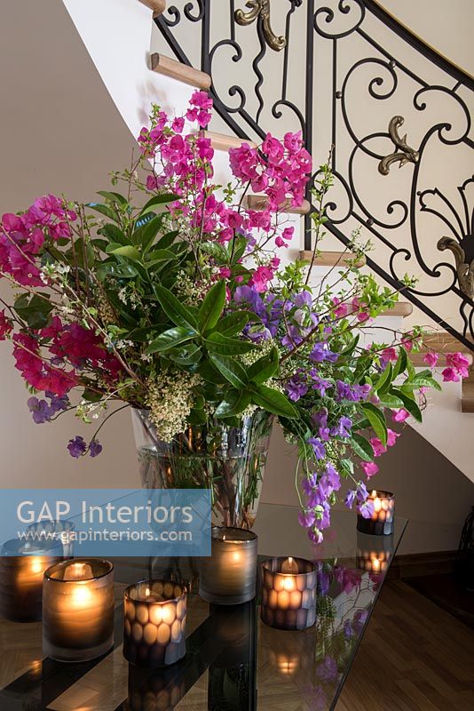 Détail de l'arrangement floral et des bougies chauffe-plat sur la table du couloir