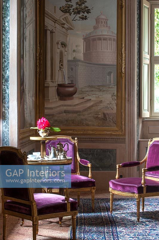Chaises anciennes violettes avec immense peinture sur le mur dans la salle de séjour en classe
