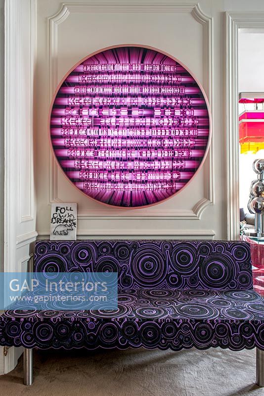 Canapé à motifs violet sous des illustrations colorées