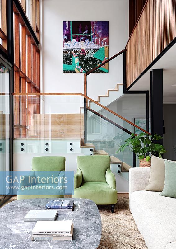 Fauteuils verts dans un salon moderne avec vue sur escalier