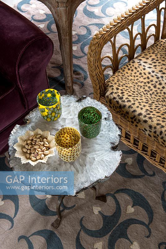 Chaise en osier avec coussin imprimé léopard et verrerie décorative sur table