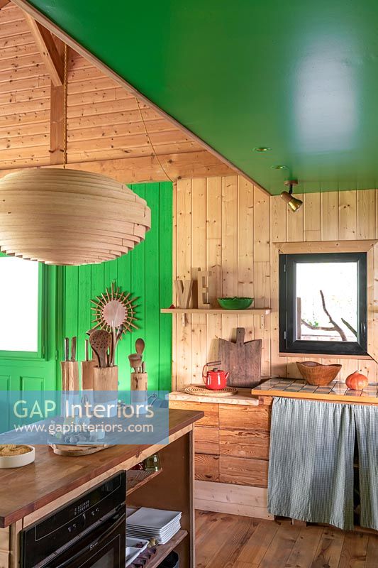 Cuisine de campagne en bois avec plafond peint en vert et mur caractéristique