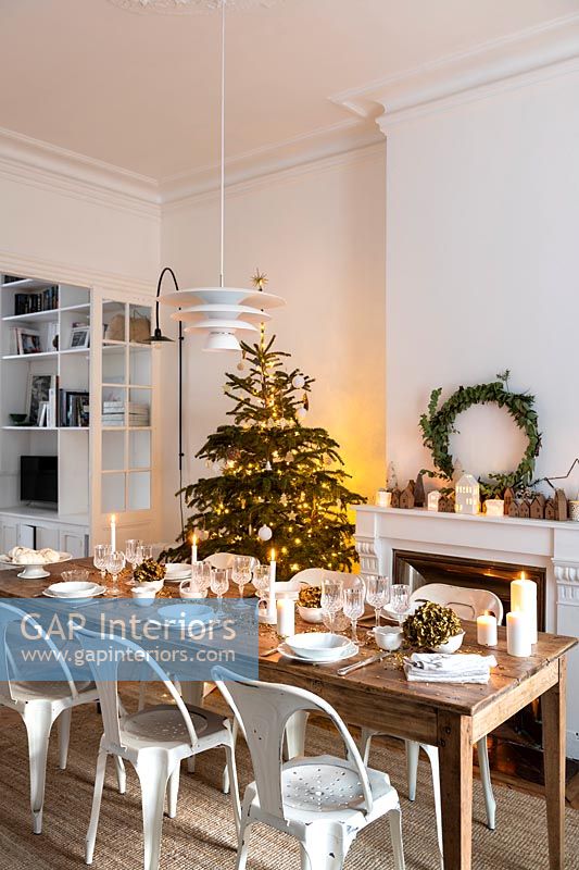 Table à manger en bois posée pour le dîner de Noël dans la salle à manger blanche