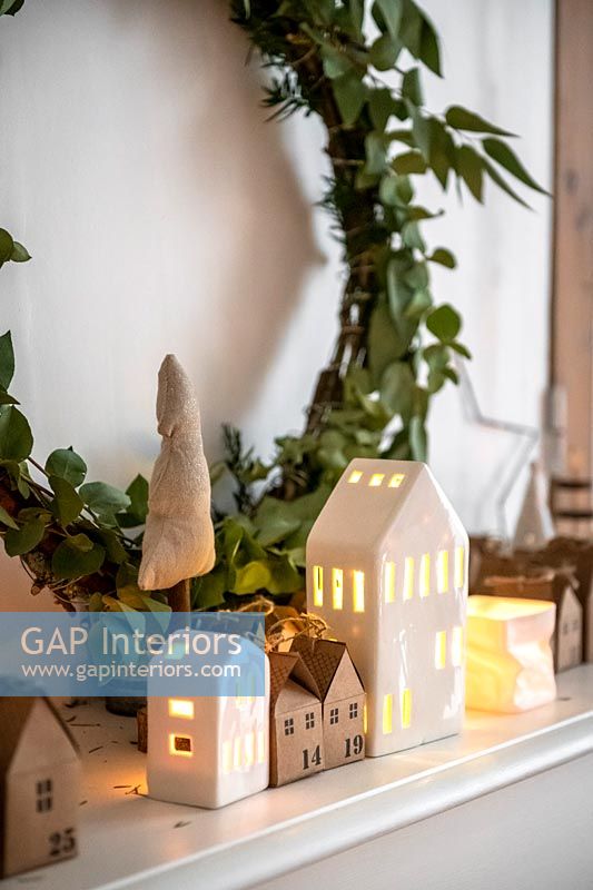 Guirlande et petites maisons avec des bougies sur la cheminée à Noël