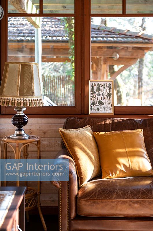 Vieux canapé en cuir marron à côté de la fenêtre dans le salon de pays