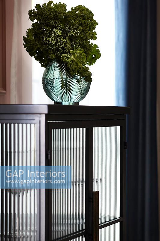 Vase en verre décoratif avec des feuilles de chou frisé sur armoire noire - détail
