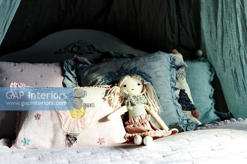 Détail de ragdoll et coussins sur le lit d'enfant