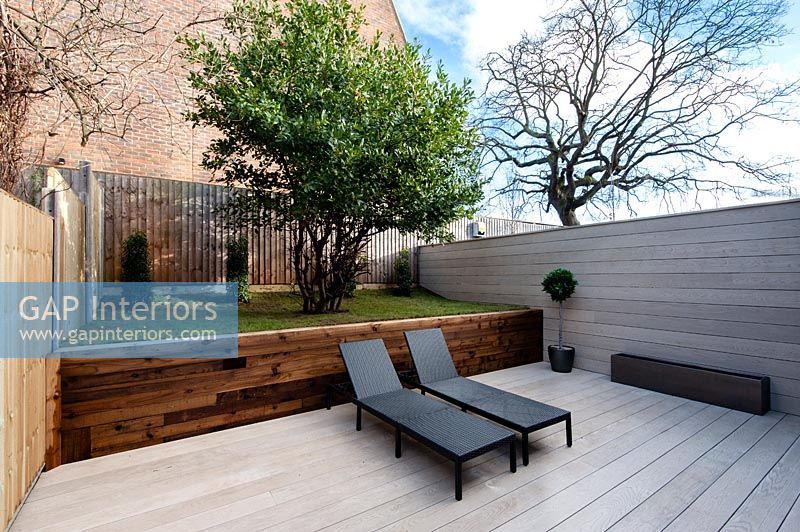 Jardin cour moderne en duplex avec fauteuils inclinables sur une terrasse