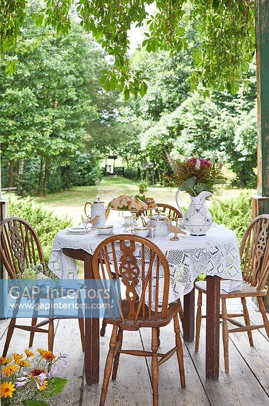 Thé de l'après-midi sur une terrasse en bois donnant sur le jardin de campagne