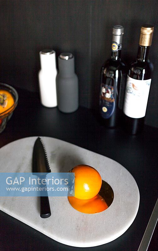 Fruit de Sharon orange sur planche à découper en marbre blanc dans la cuisine noire