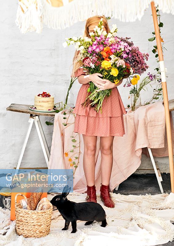 Jeune femme tenant un grand bouquet de fleurs coupées avec lapin de compagnie