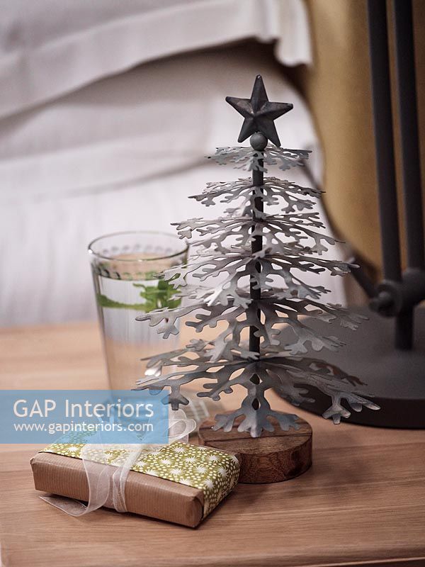 Sapin de Noël miniature et cadeau sur table de chevet