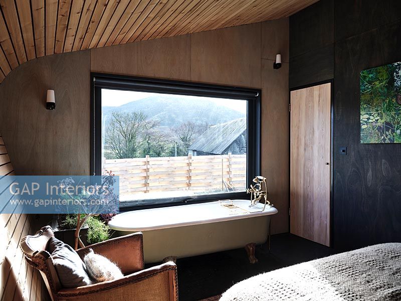 Baignoire à côté de la fenêtre dans la chambre en bois moderne