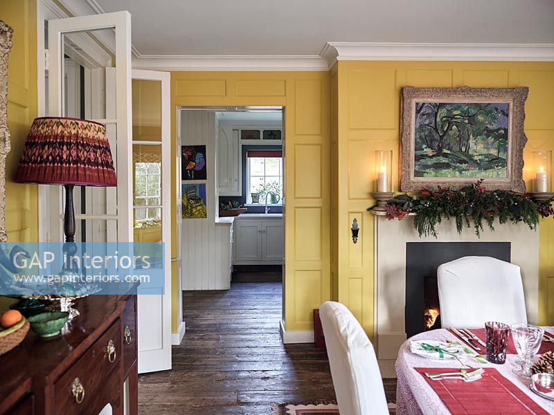 Vue dans la cuisine de la salle à manger lambrissée peinte jaune